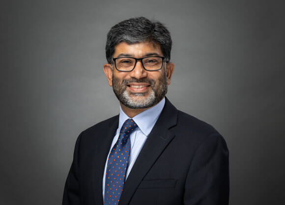 Dr. Khuram Ghumman smiling against a grey background