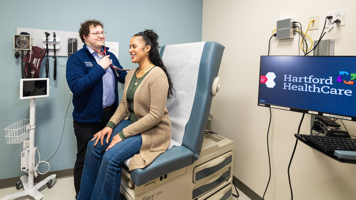 A student performing an exam on a patient in a doctors office.