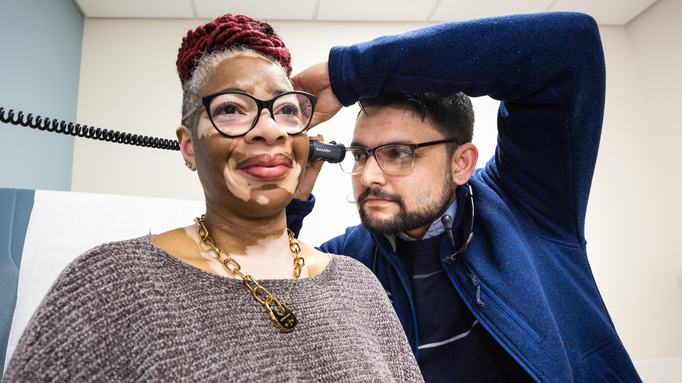 A patient getting her ear examined by a medical student.