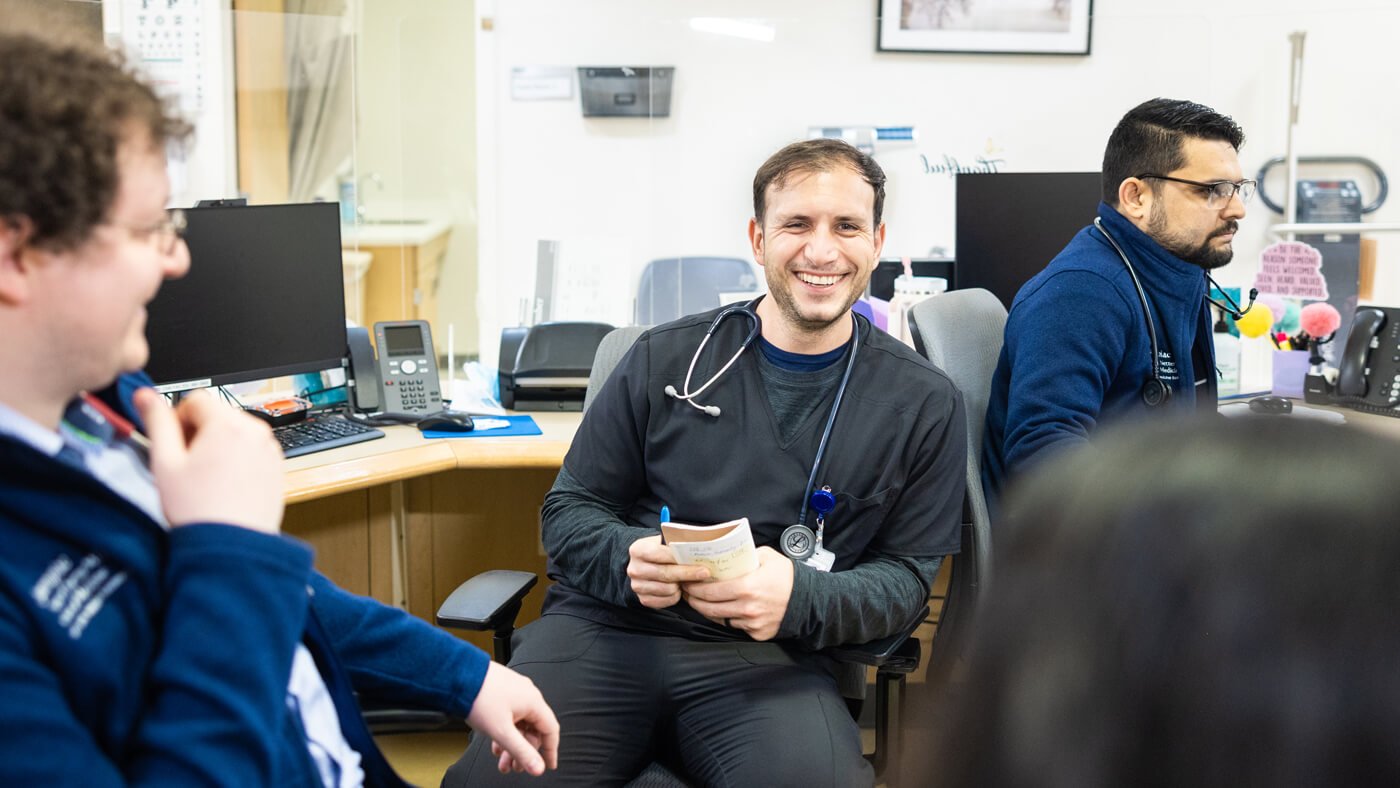 Medical students and colleagues conversing in an office environment.