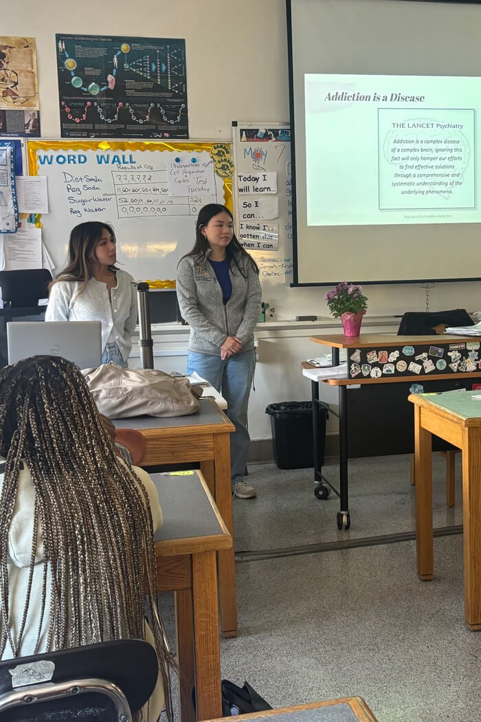 Students giving a presentation in a grade-school classroom setting.